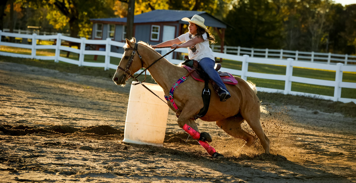 Ella Nipper is riding her palomino horse and turning a barrel. 